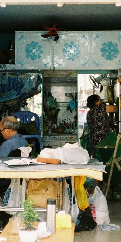 A bustling tailor workshop with two people engaged in sewing and organizing materials.