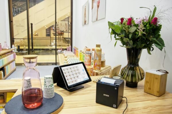 A stylish store checkout counter featuring a floral bouquet and digital payment system.