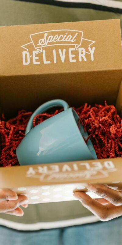 Man holding a box with a special delivery coffee mug inside.